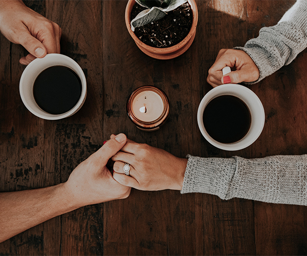 Couple holding hands over coffee